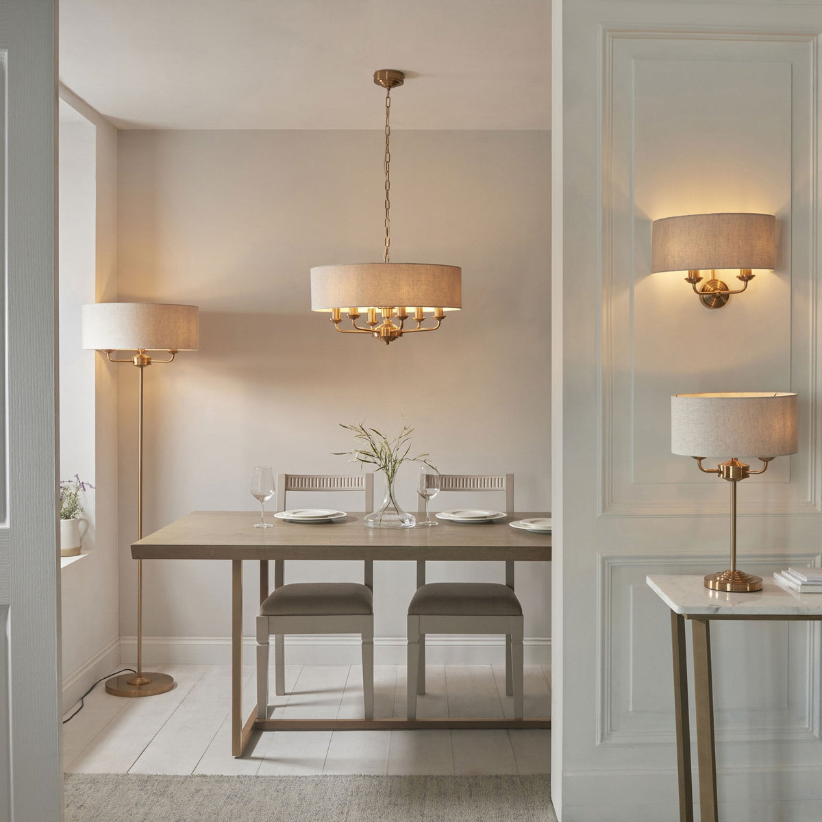 A dining room with a chandelier, floor lamp, wall sconce, and table lamp, all with light fabric shades.