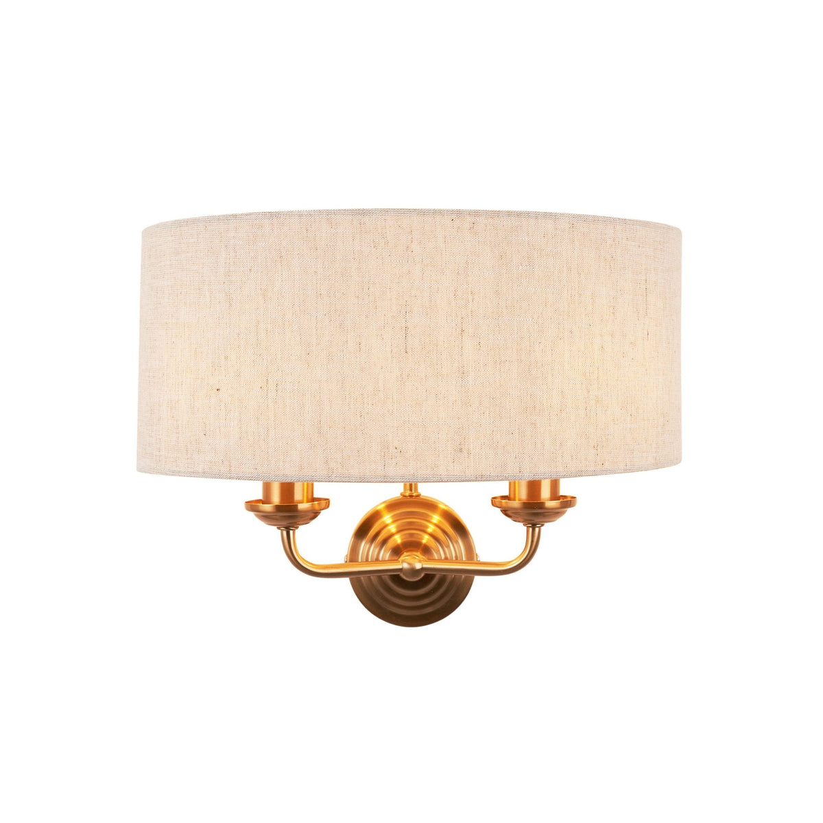 An antique brass wall light with a natural linen drum shade on a white background.