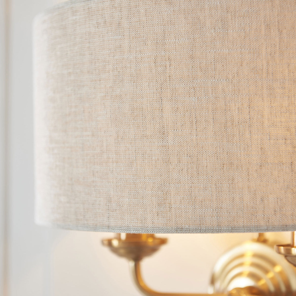 Close-up of the natural linen drum shade of an antique brass wall light.