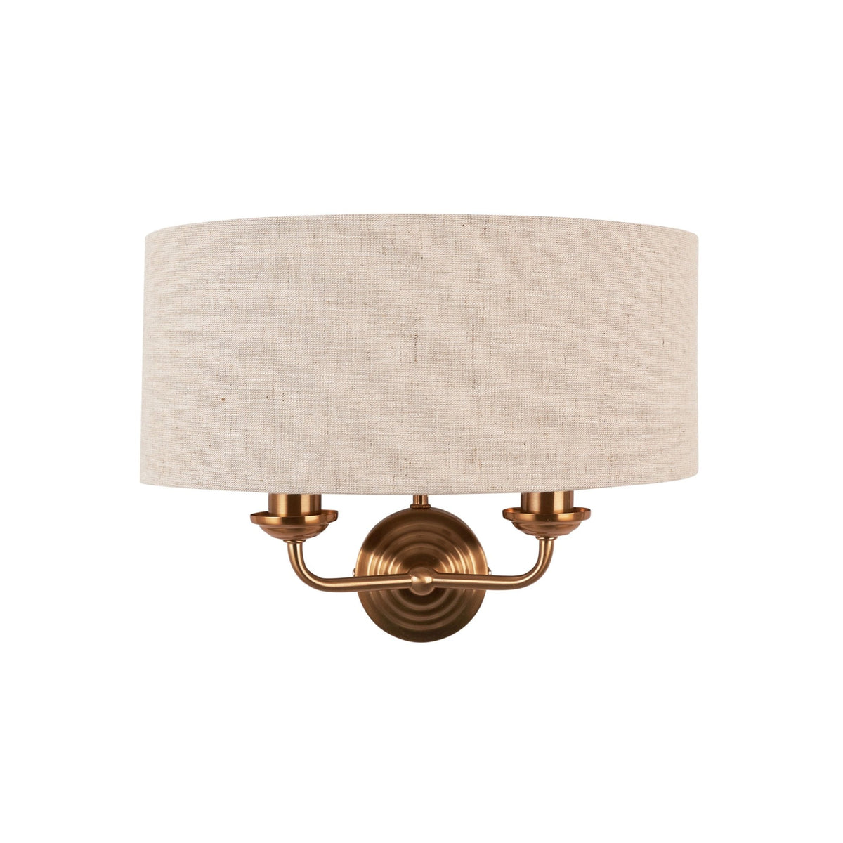 An antique brass wall light with a natural linen drum shade on a white background.
