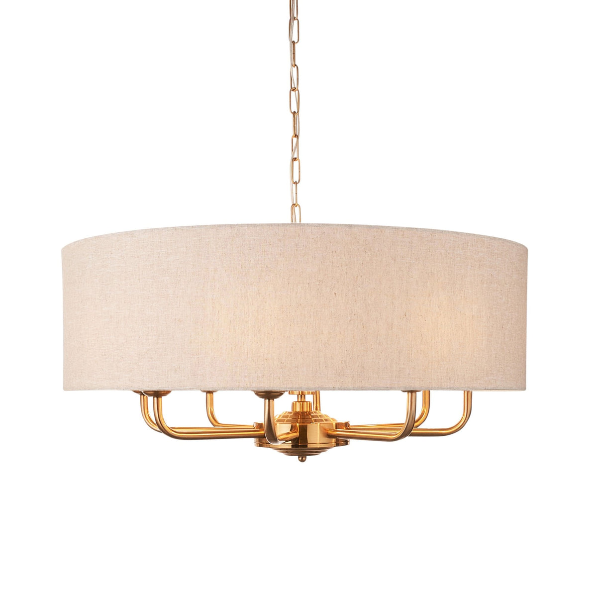 A gold chandelier with a light fabric drum shade on a white background.