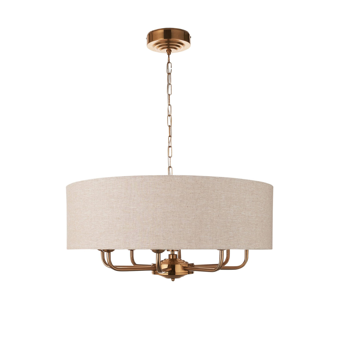 A gold chandelier with a light fabric drum shade on a white background.