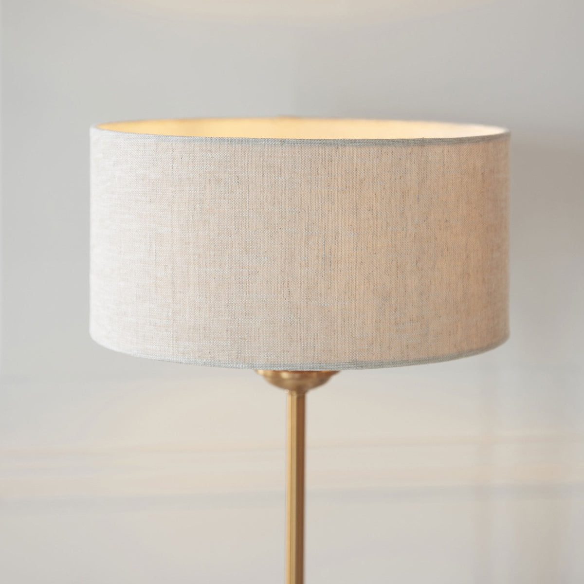 Close-up of a brass table lamp with a light linen drum shade.