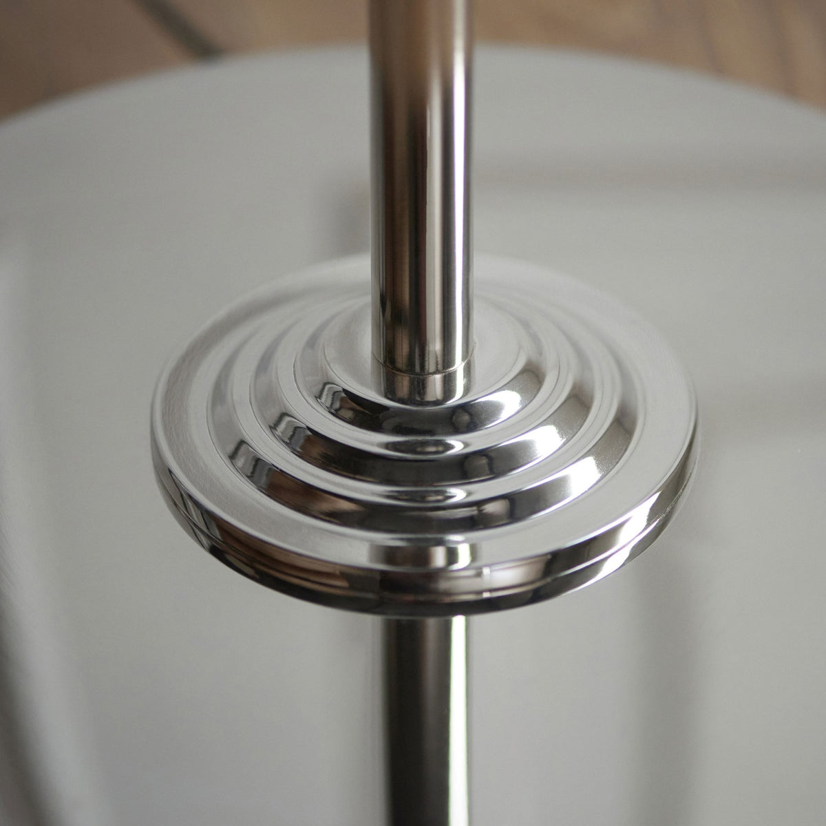 Close-up of the polished silver, stepped base of a floor lamp.