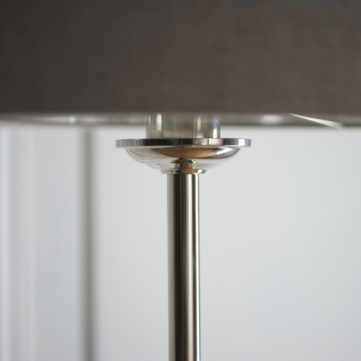 Close-up of the connection between the silver pole and the dark grey lampshade of a floor lamp.