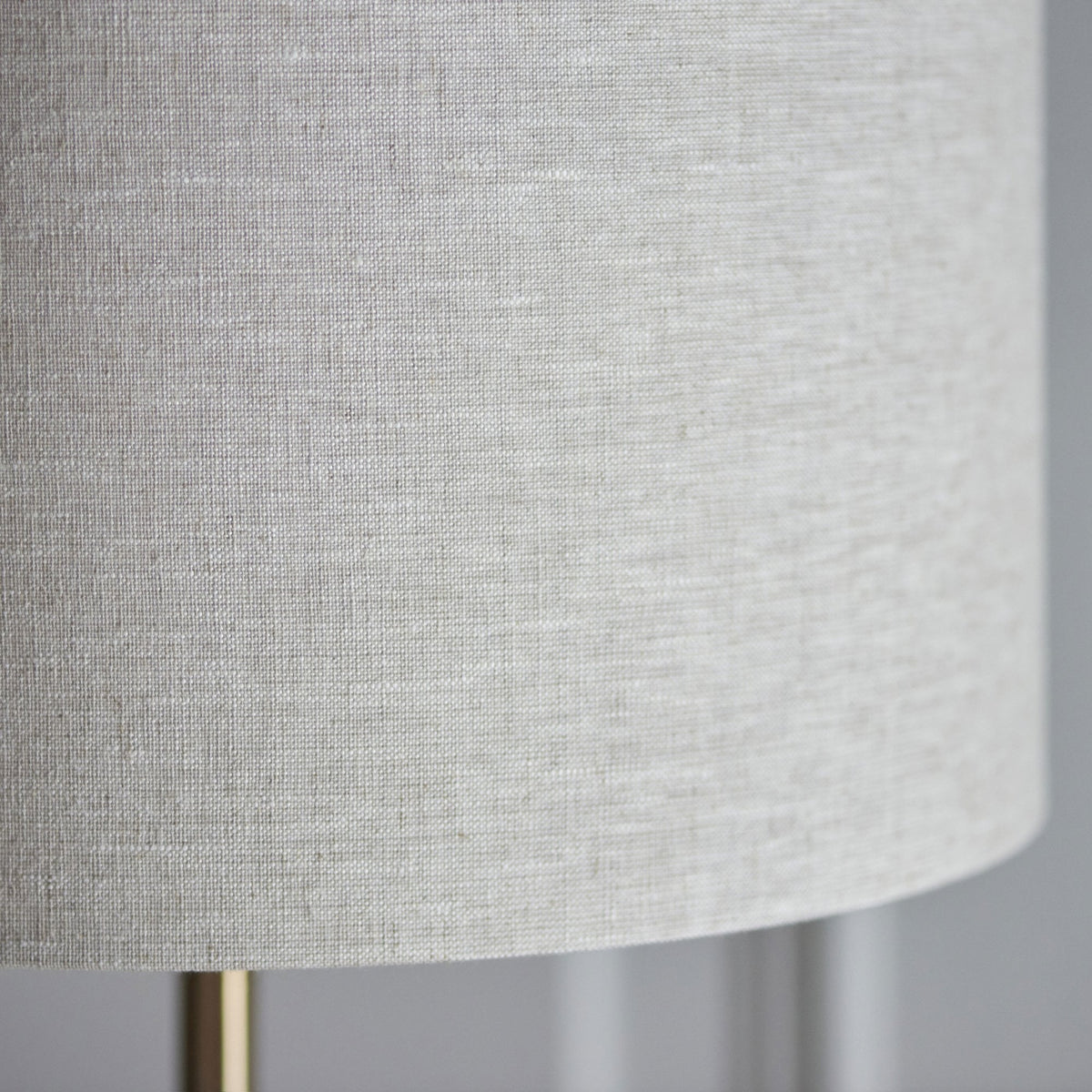 Close-up of the textured, light gray linen fabric of a drum lampshade.