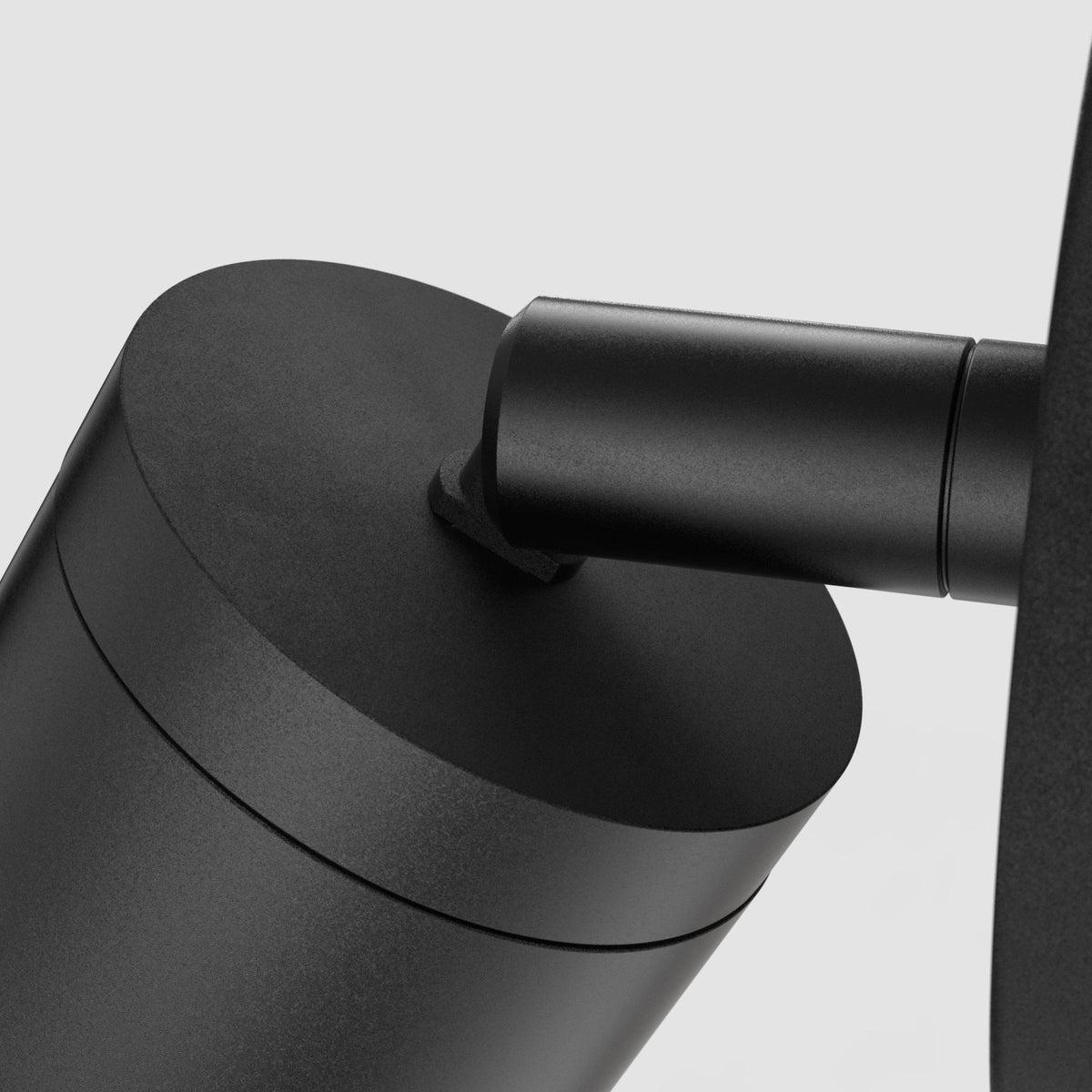Close up of a black cylindrical light fixture with a connecting arm