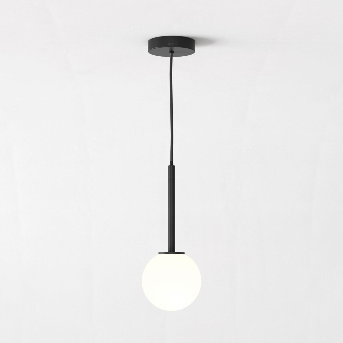 A black pendant light with a spherical white glass shade hangs from the ceiling