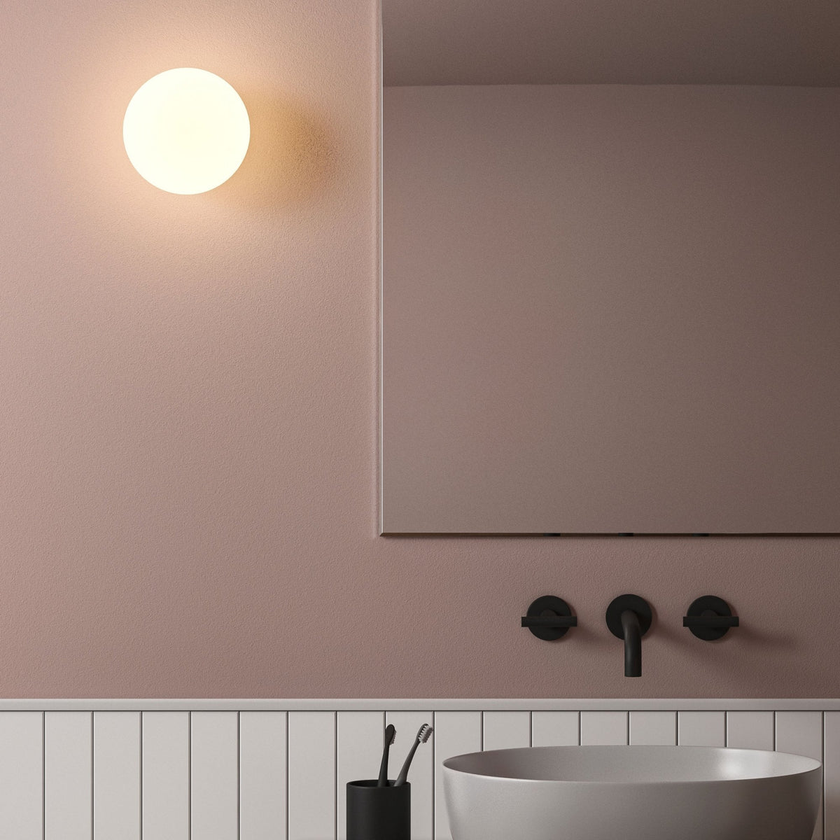 A white orb wall light in a modern bathroom with a sink and mirror.