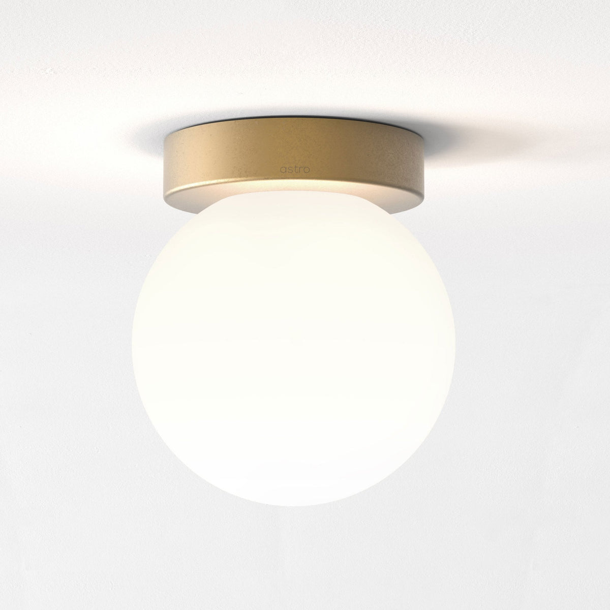 Astro ceiling light with a gold base and a round white glass shade