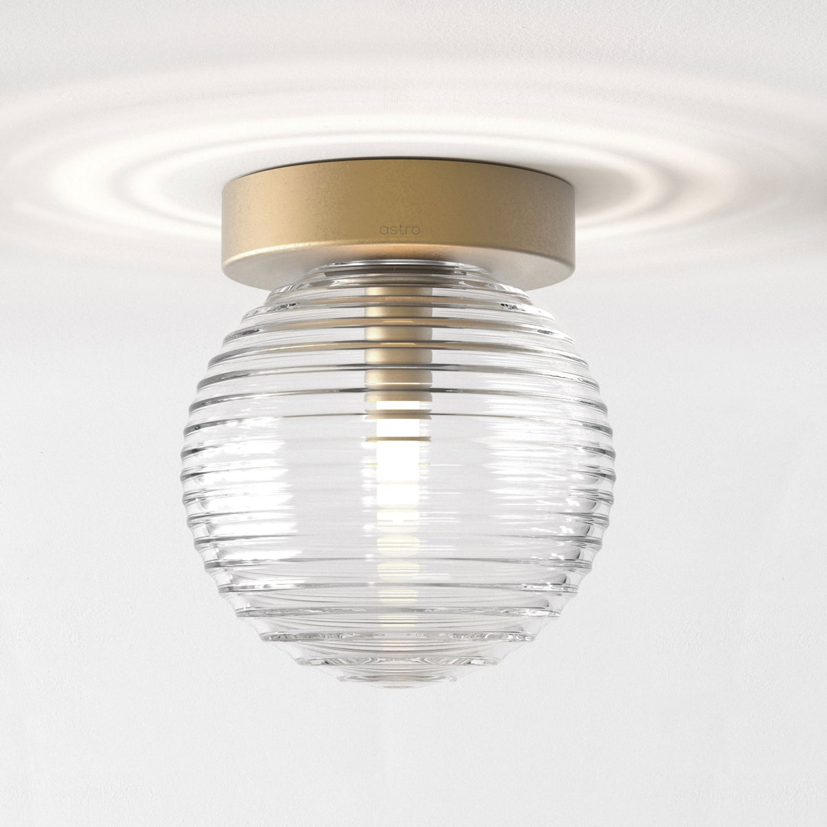 Astro branded ceiling light with a gold base and a clear, ribbed glass shade