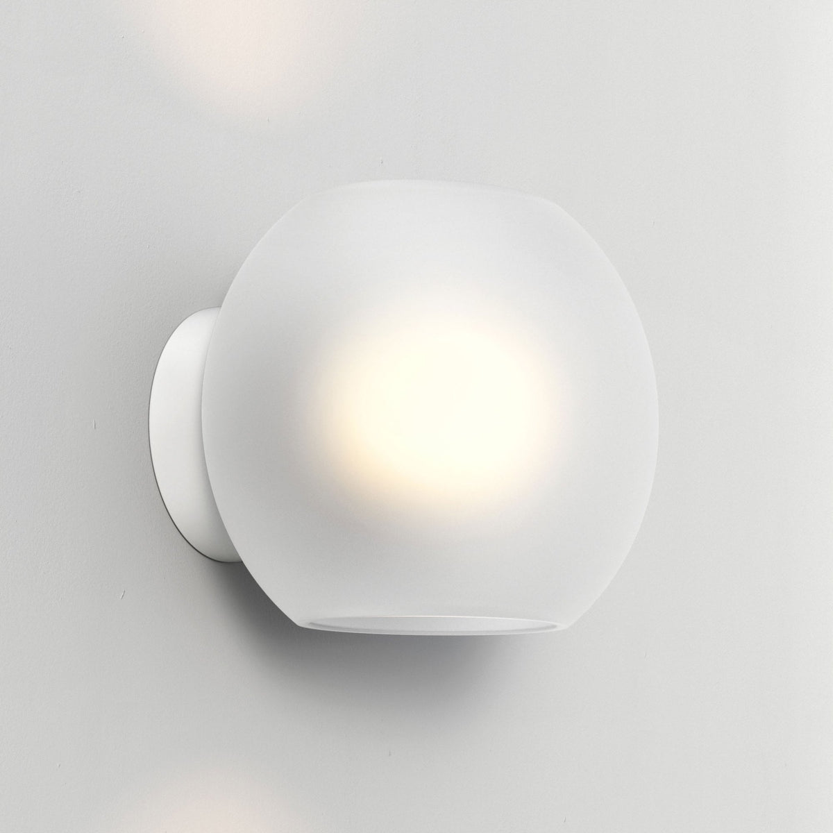 White frosted glass globe wall light with a bright glow