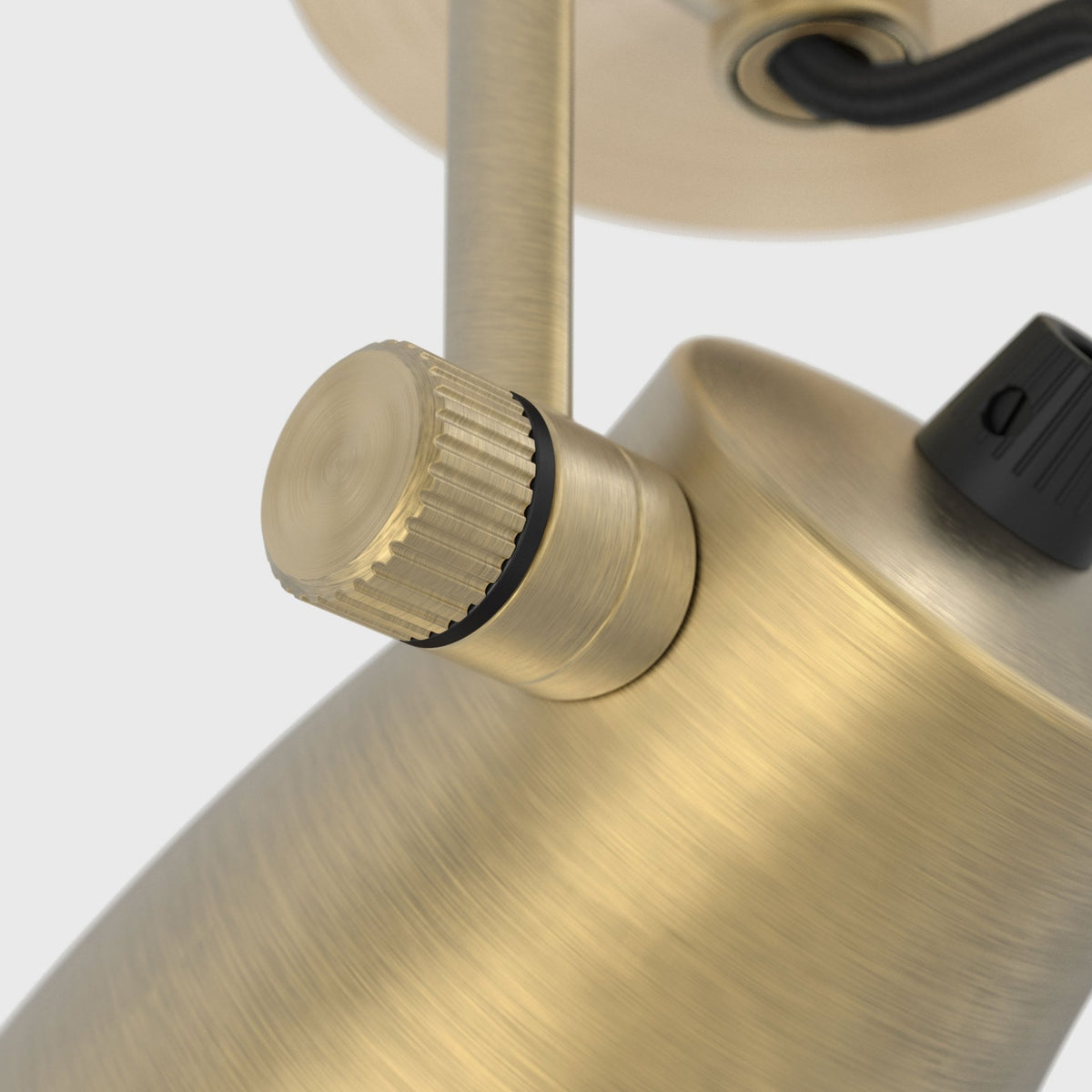Close up of a brass light fixture with a textured knob and black wire