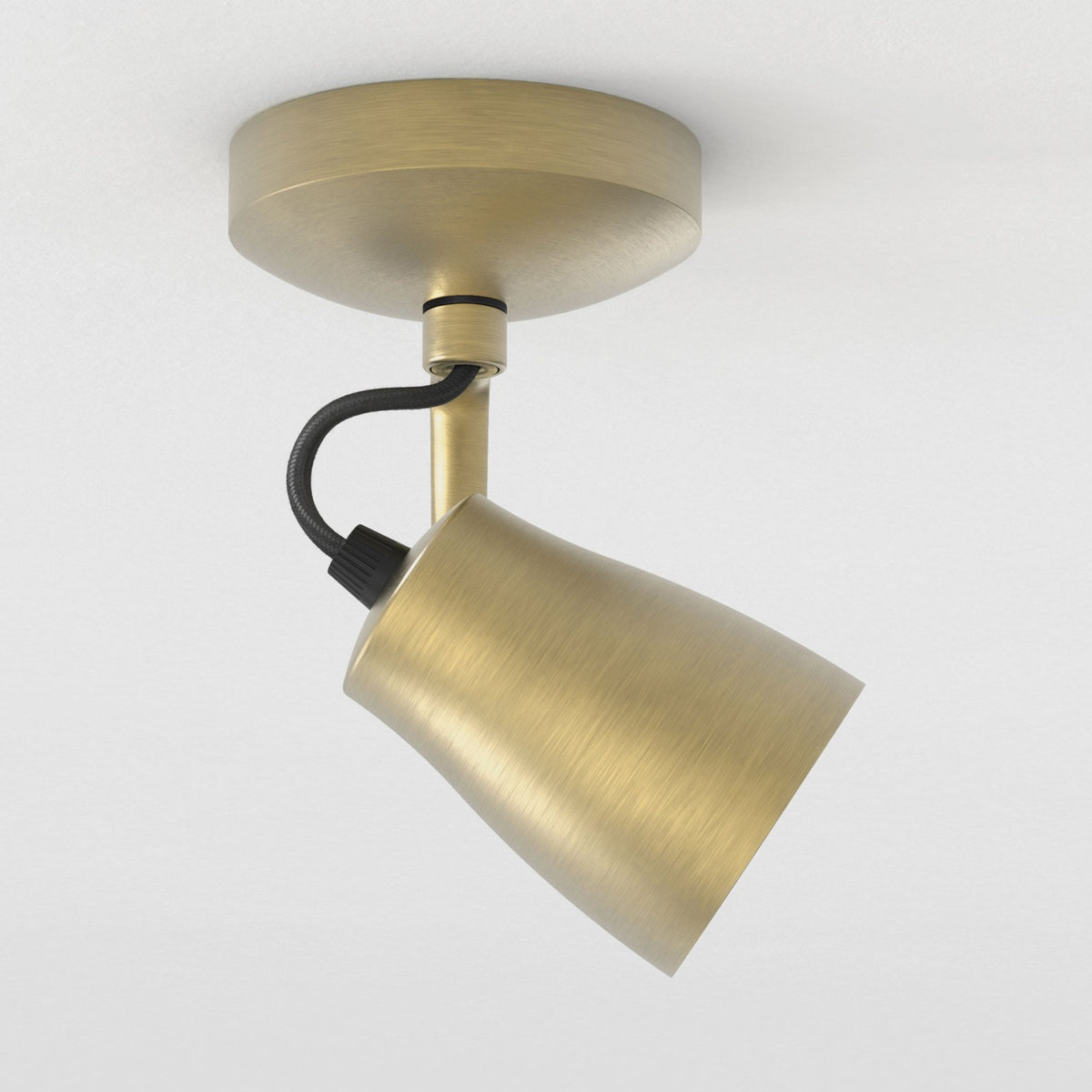 Brushed brass ceiling spotlight with a black fabric cable