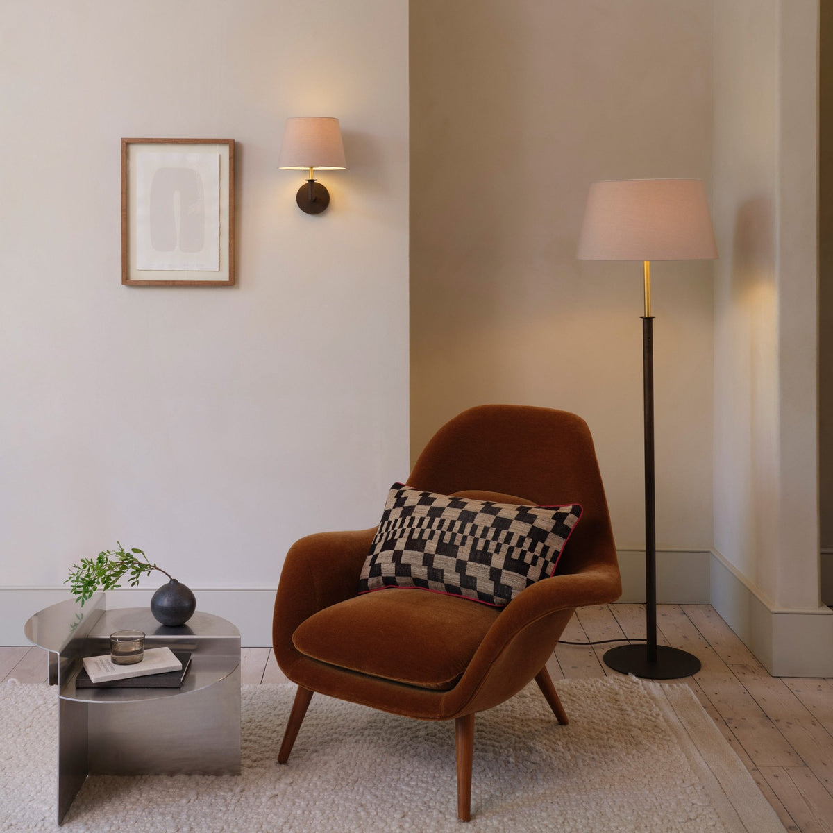 A brown armchair with a patterned cushion, a metal side table, and a floor lamp in a living room