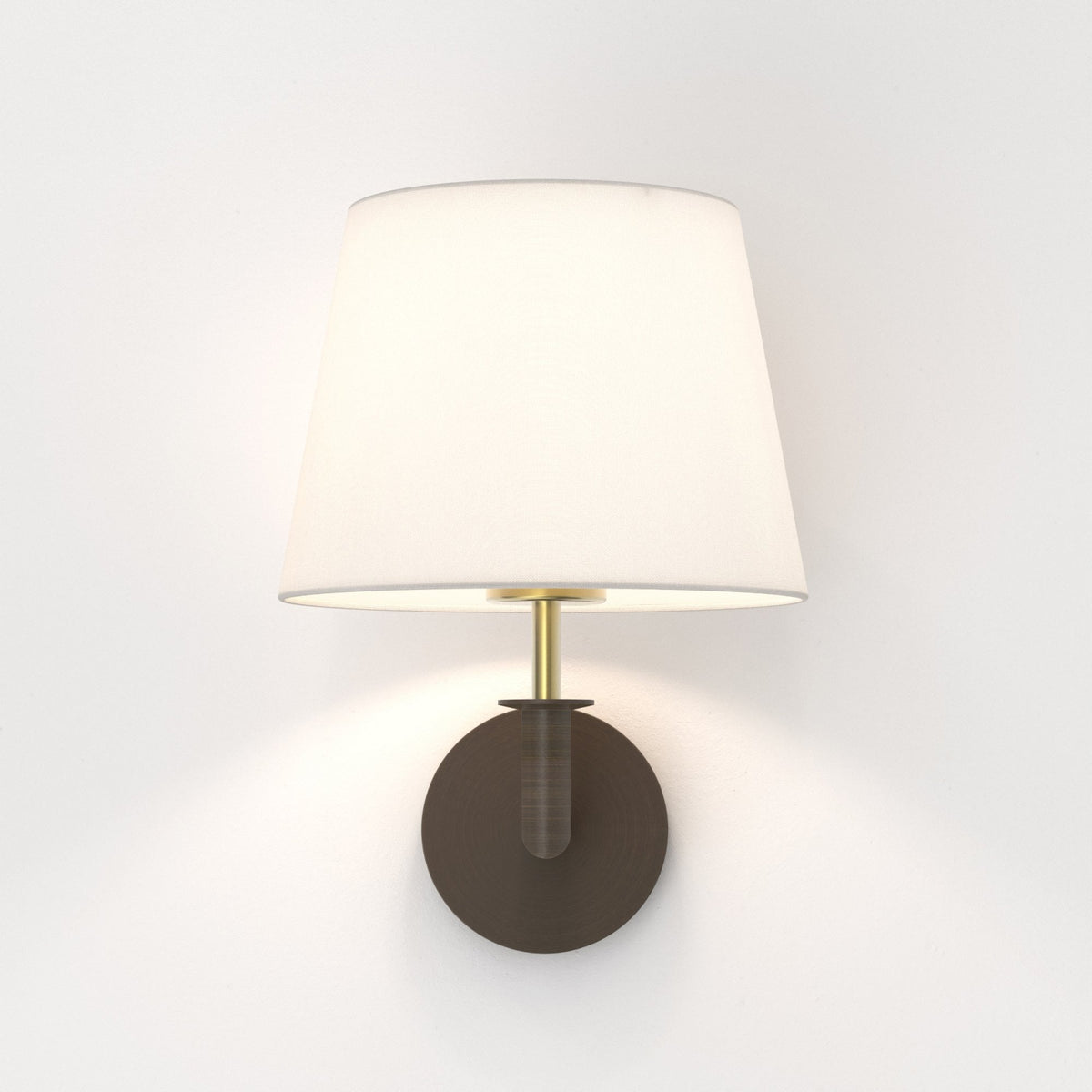 Wall sconce with a white fabric shade, brass stem, and dark bronze circular base