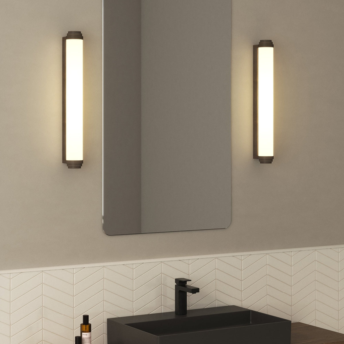 Two vertical wall sconces with a rectangular mirror and a black sink with a black faucet