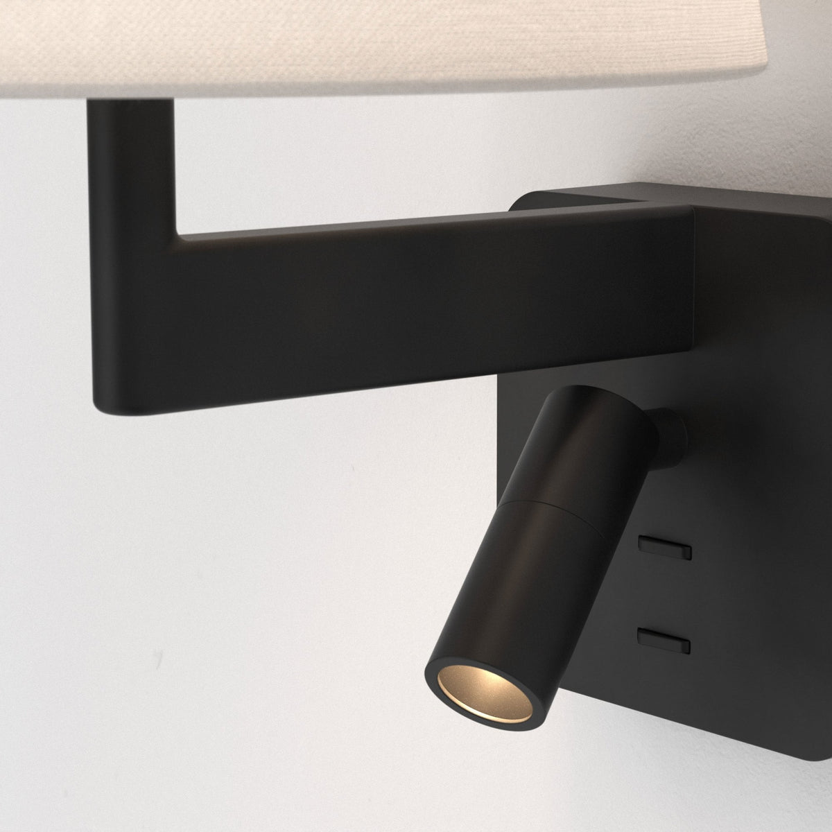 Black wall-mounted lamp with a white fabric shade and an adjustable spotlight