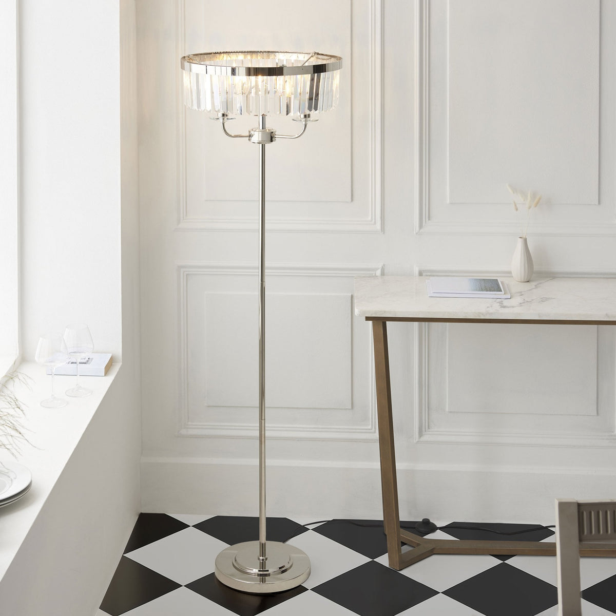 Lampadaire élégant avec abat-jour en cristal, éclairant une pièce aux carreaux noirs et blancs.