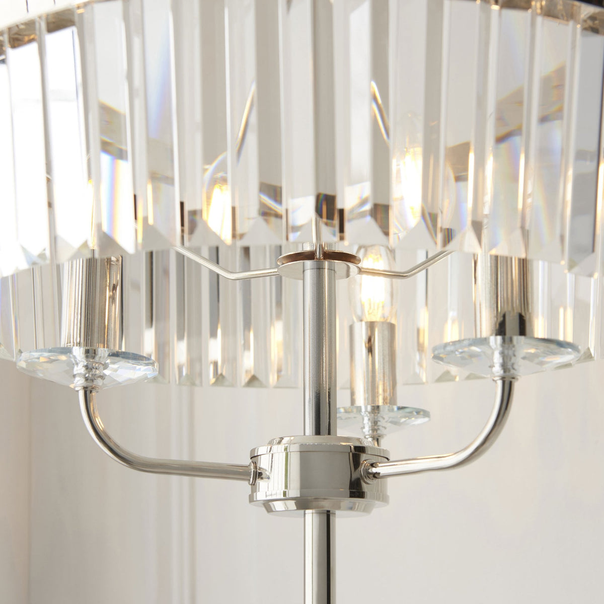 Gros plan de l'abat-jour en cristal taillé d'un lampadaire, révélant les ampoules allumées.