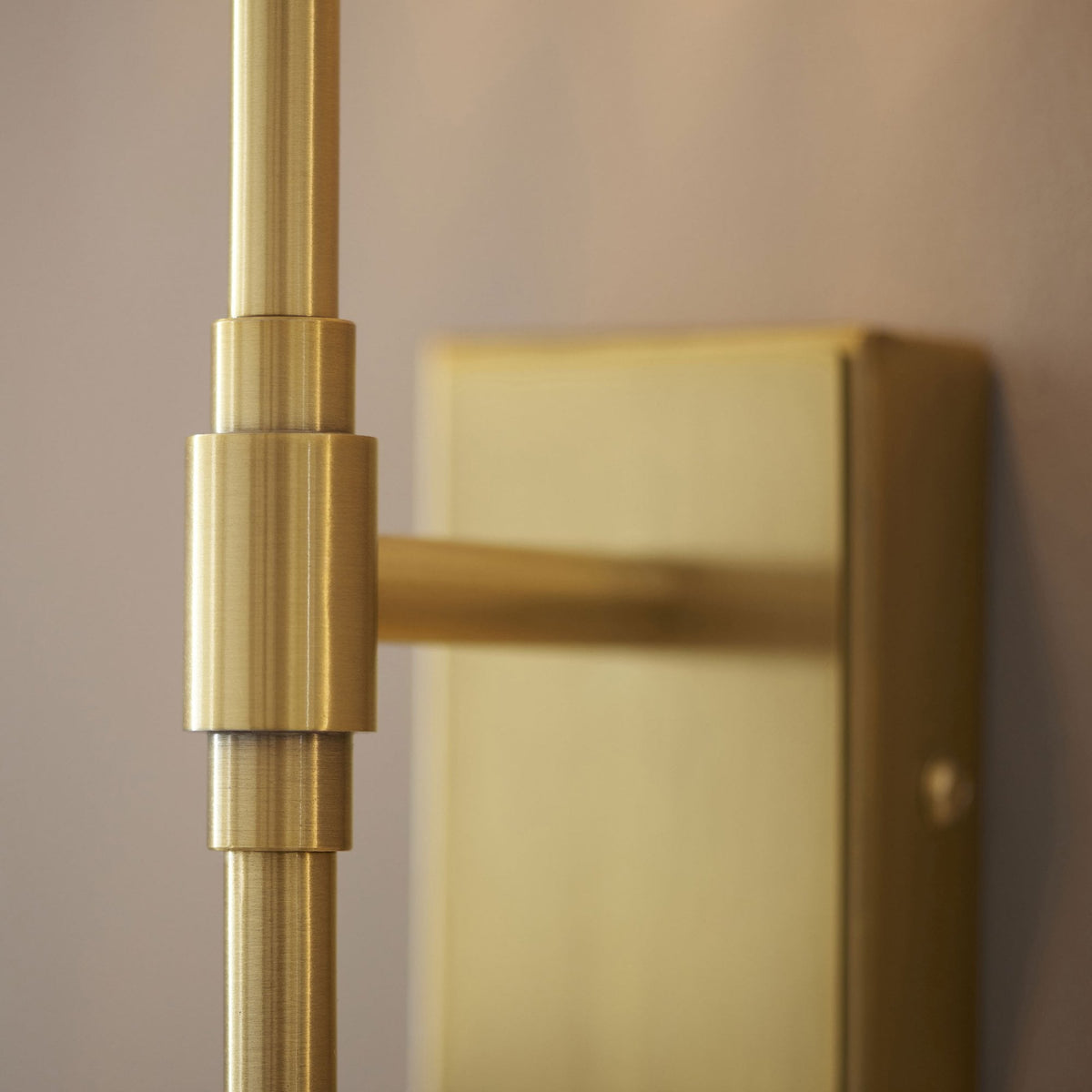 Détail d'un luminaire doré moderne, mettant en valeur la finition métallique brossée et le design élégant des joints.