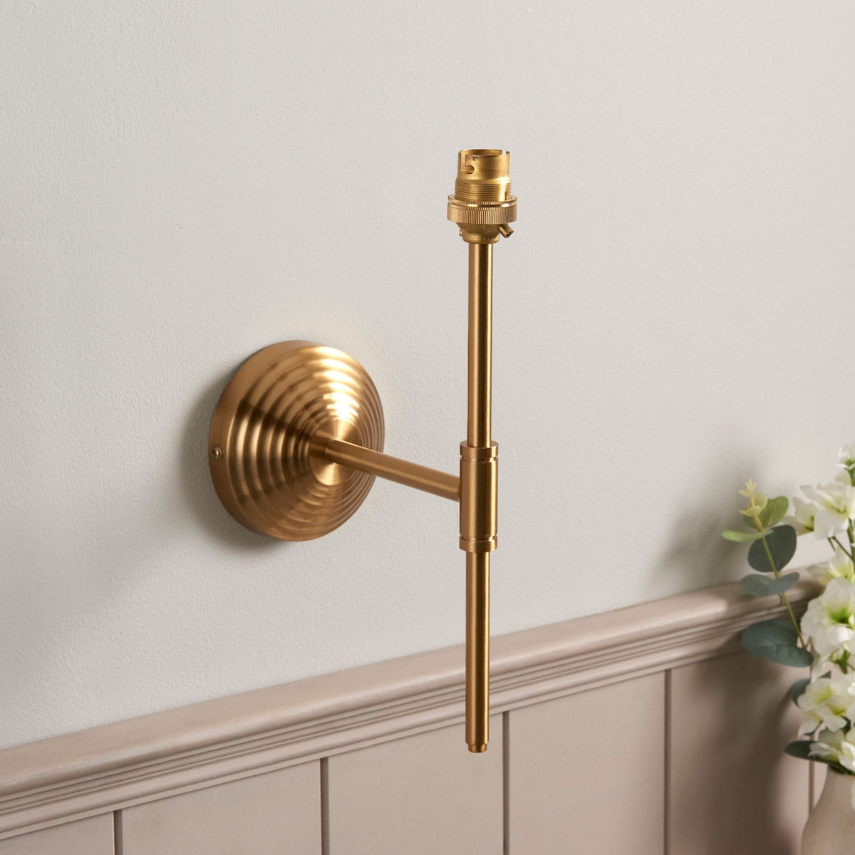 A brass wall light without a lampshade, showing the bulb fitting.