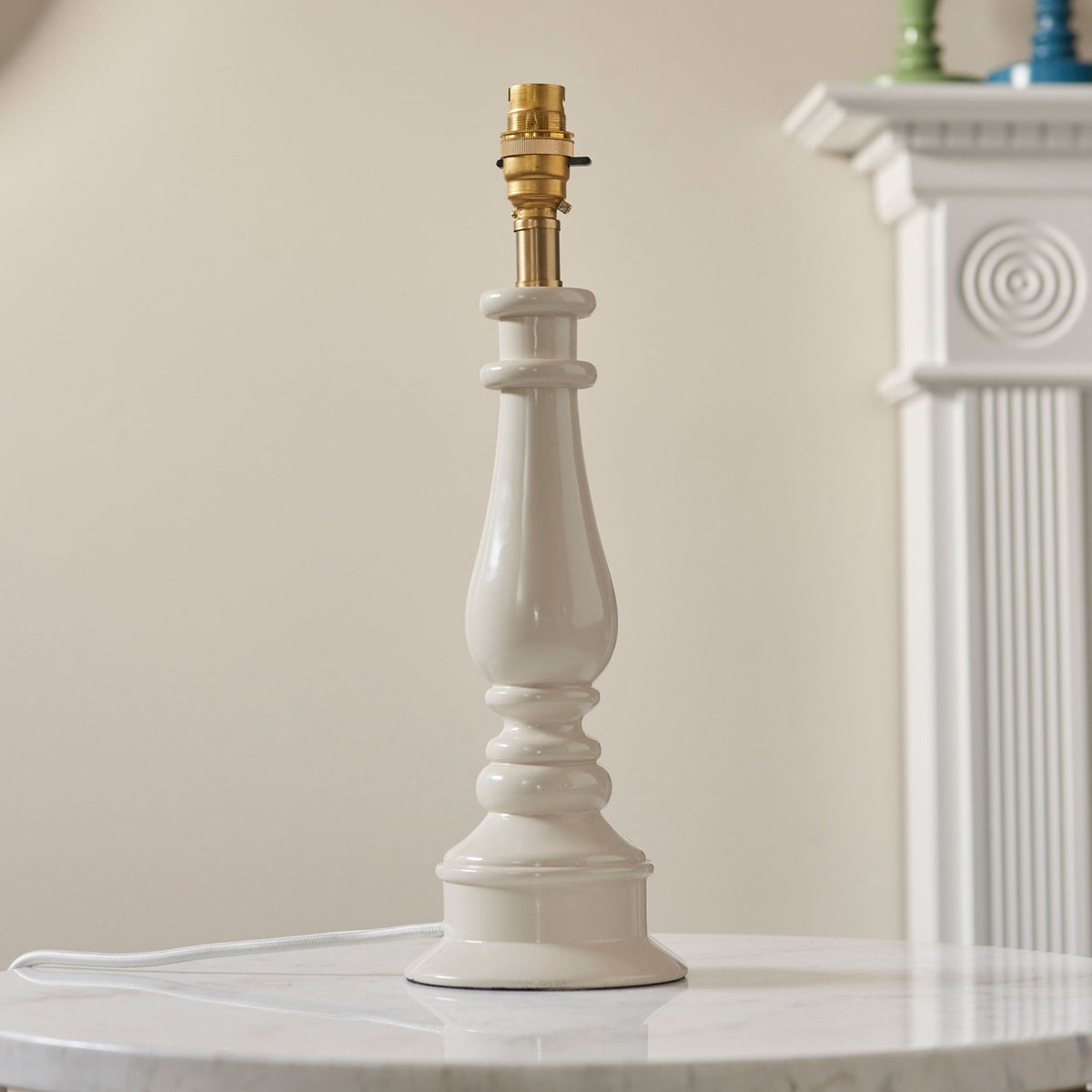A cream-coloured fluted table lamp base without a shade, showing the brass bulb holder.