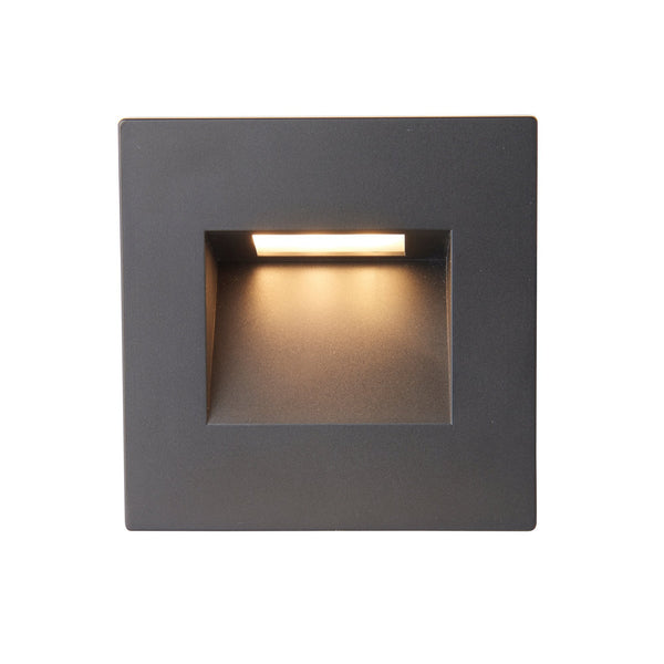 A black square recessed wall light with warm light.