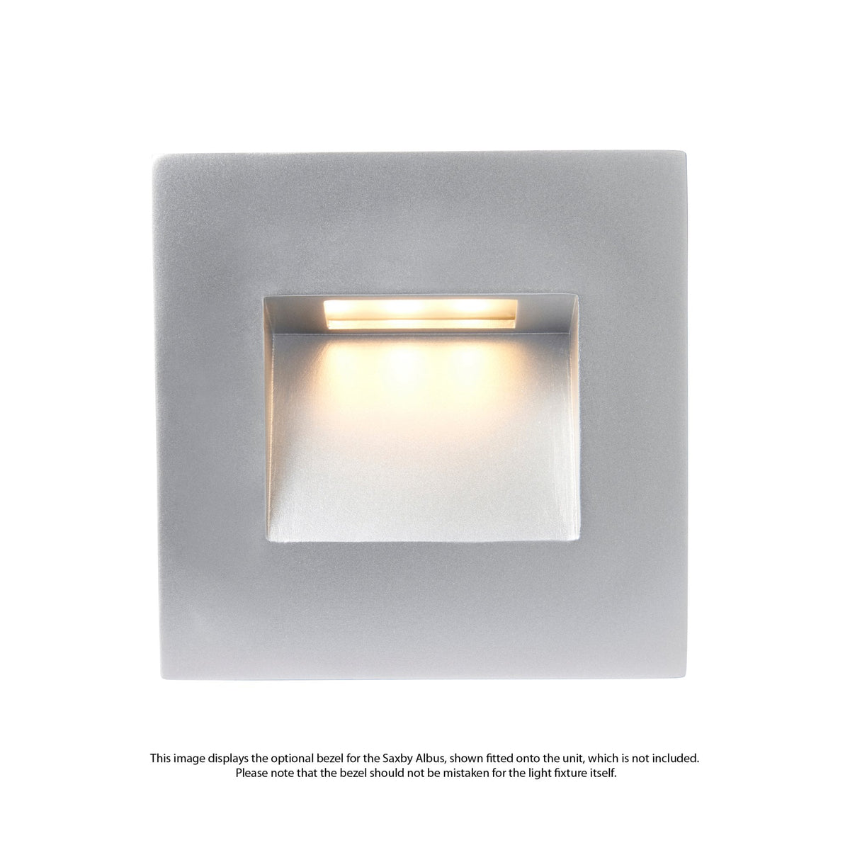 A square, silver-coloured recessed wall light with a warm yellow glow from its opening.