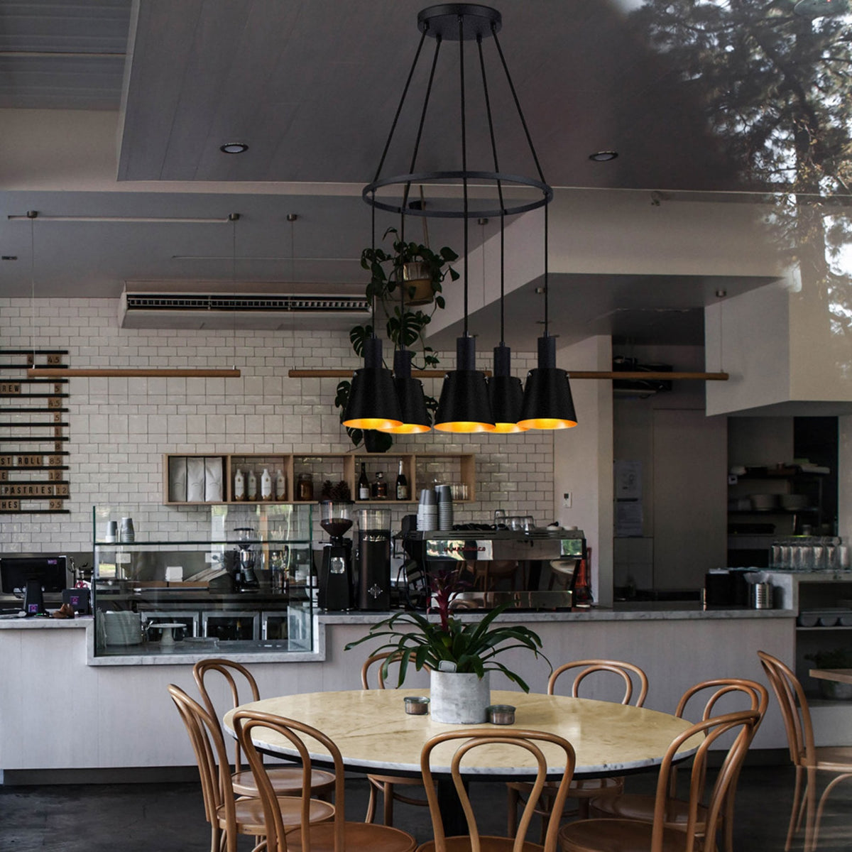 Modern black chandelier with five lights hanging over a round table in a cafe setting.