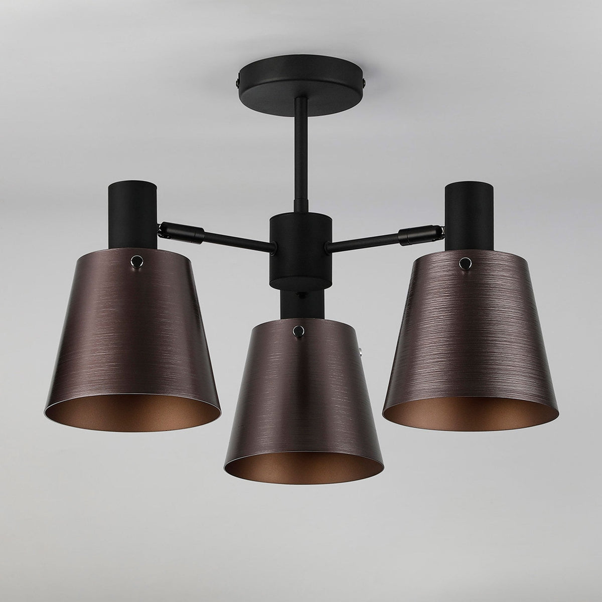 A three-arm ceiling light with aged bronze shades installed on a pale ceiling.