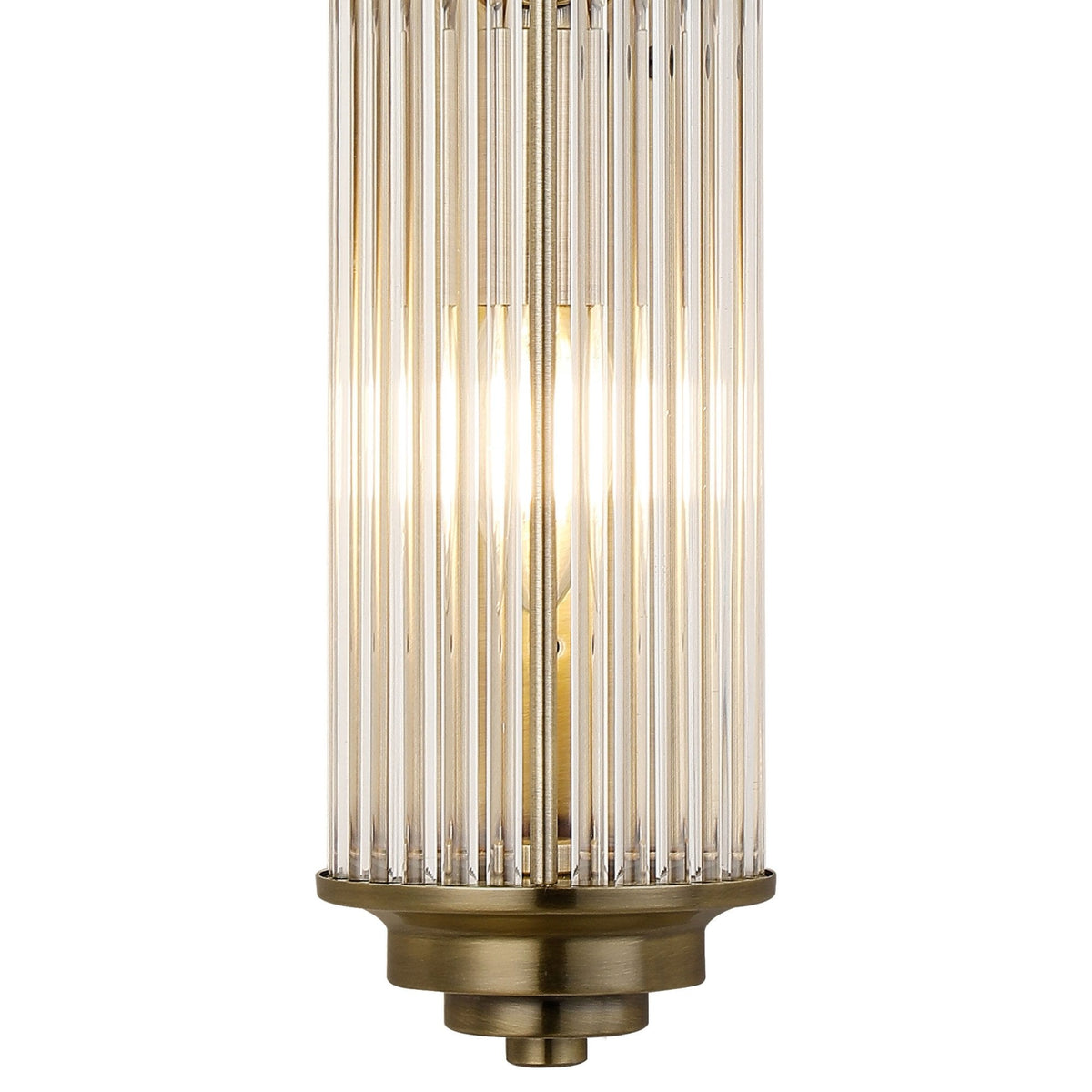 A close-up of the bottom of the ornate brushed brass reeded glass wall light with two bulbs.