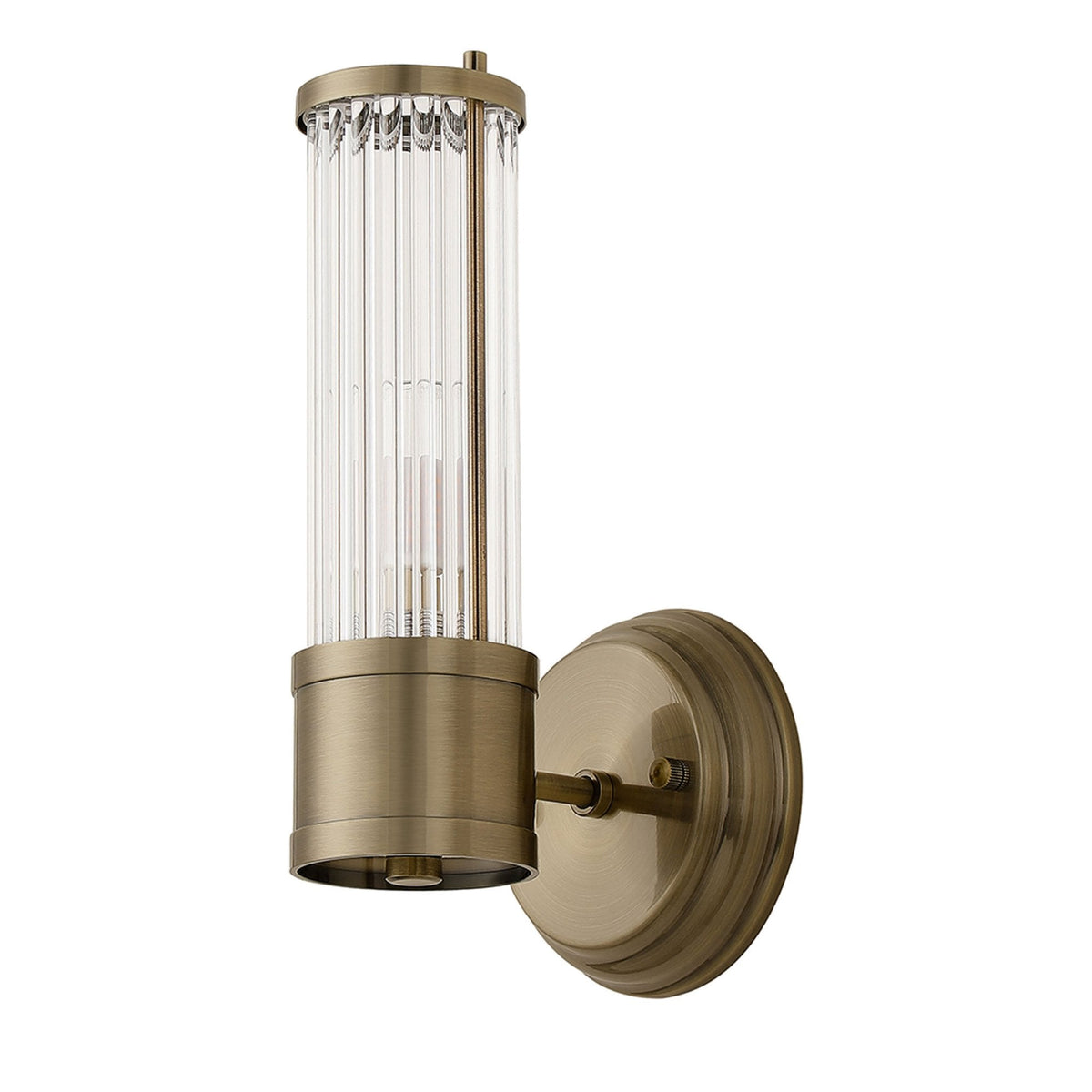 A brass wall light with a fluted glass cylinder shade, unlit, against a white background.