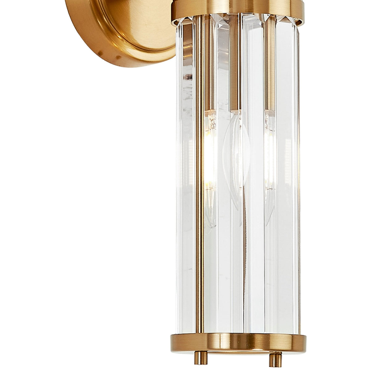 A close-up of the glowing modern brass and fluted glass wall light against a white background.