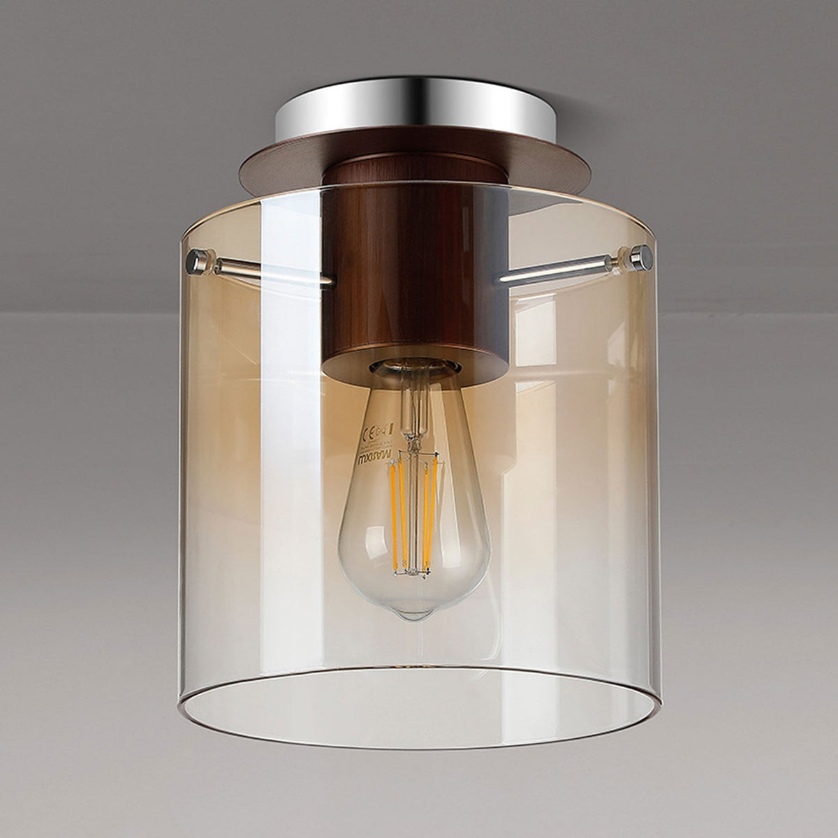 A close-up of a ceiling light featuring a clear, cylindrical amber-tinted glass shade.