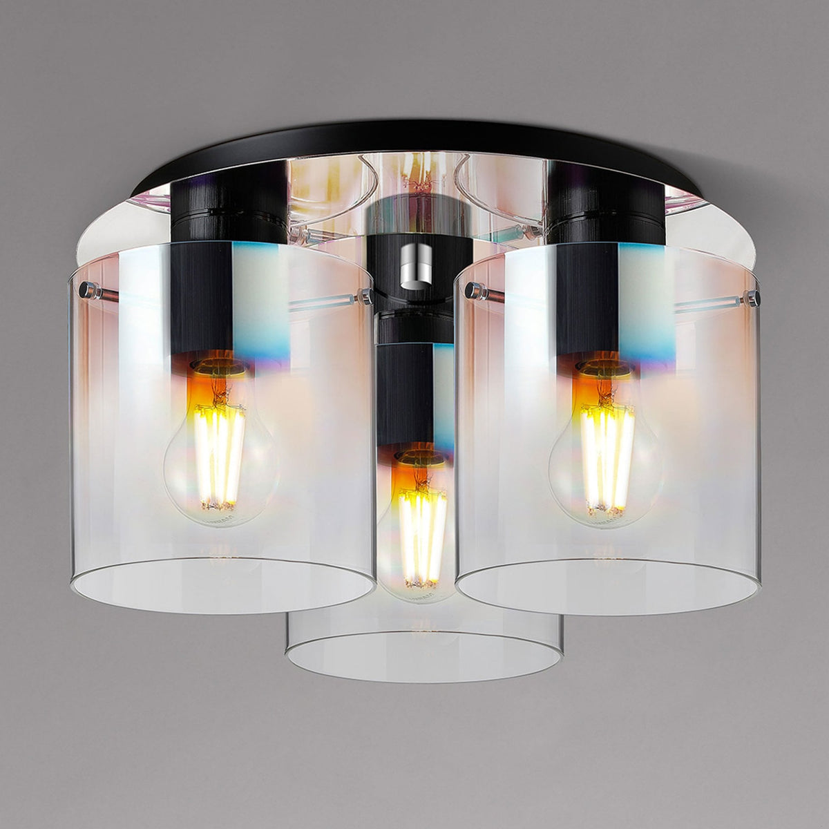 Sleek modern ceiling light fixture with three clear glass shades and exposed filament bulbs.