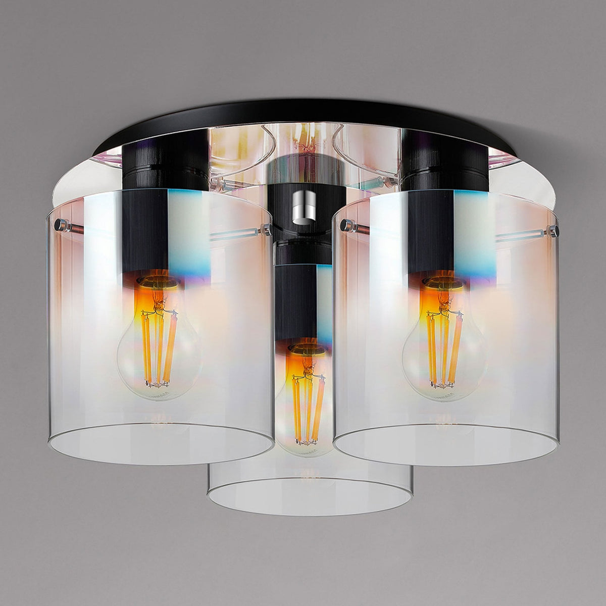 Three-bulb ceiling light with clear glass shades and visible filament bulbs, creating warm light.