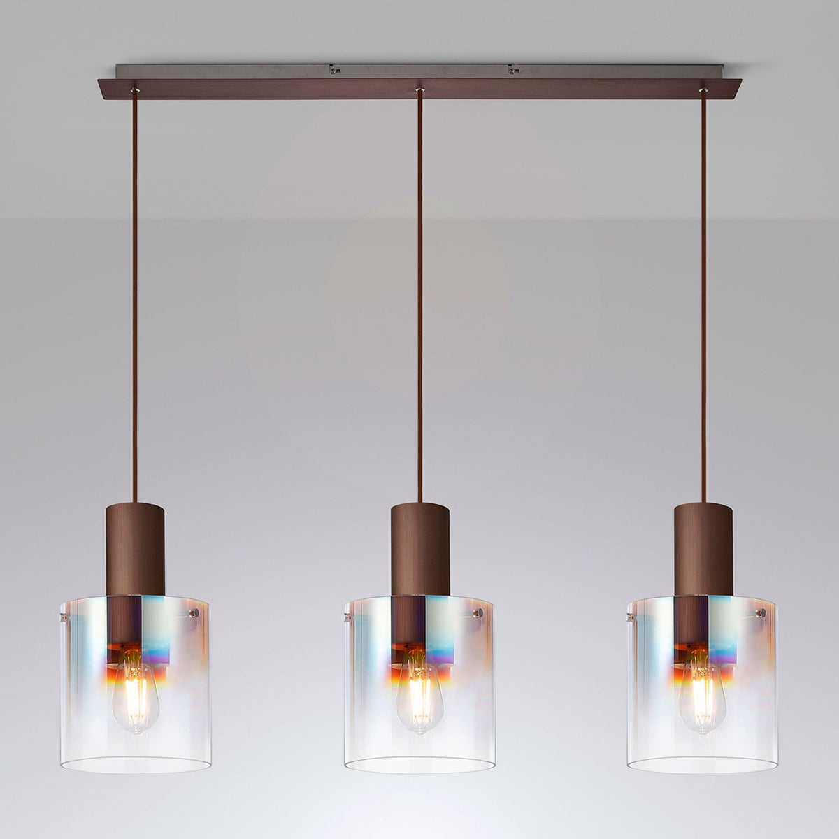 Three pendant lights with clear glass shades and bronze bases hanging from a bar.