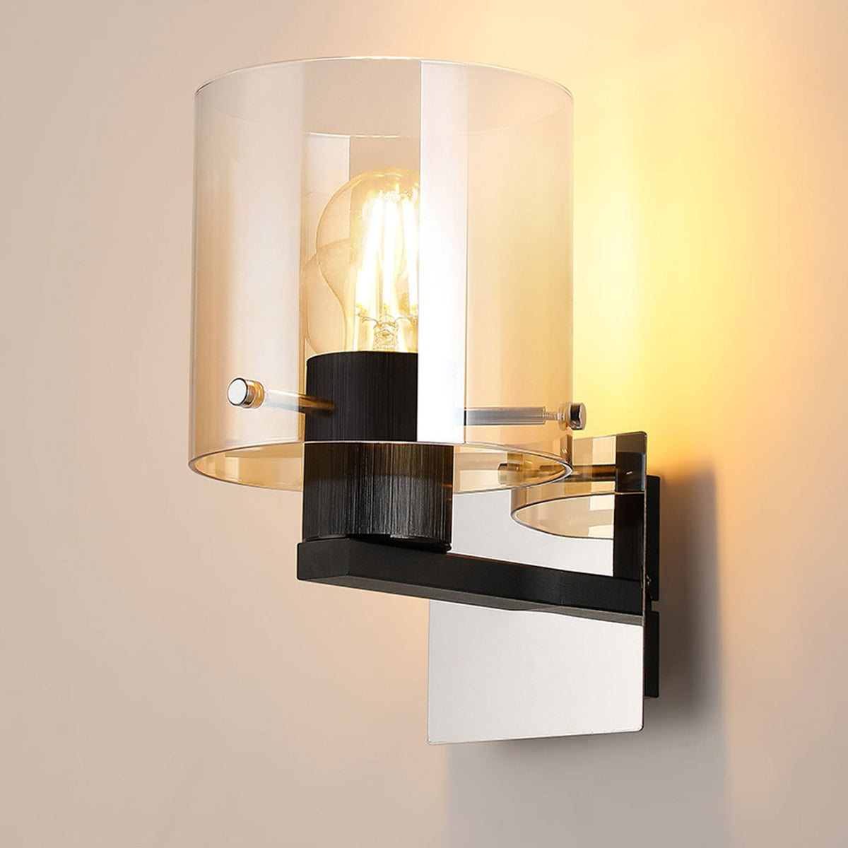 A contemporary wall light with a clear and amber glass shade, black base, and visible bulb, illuminated.