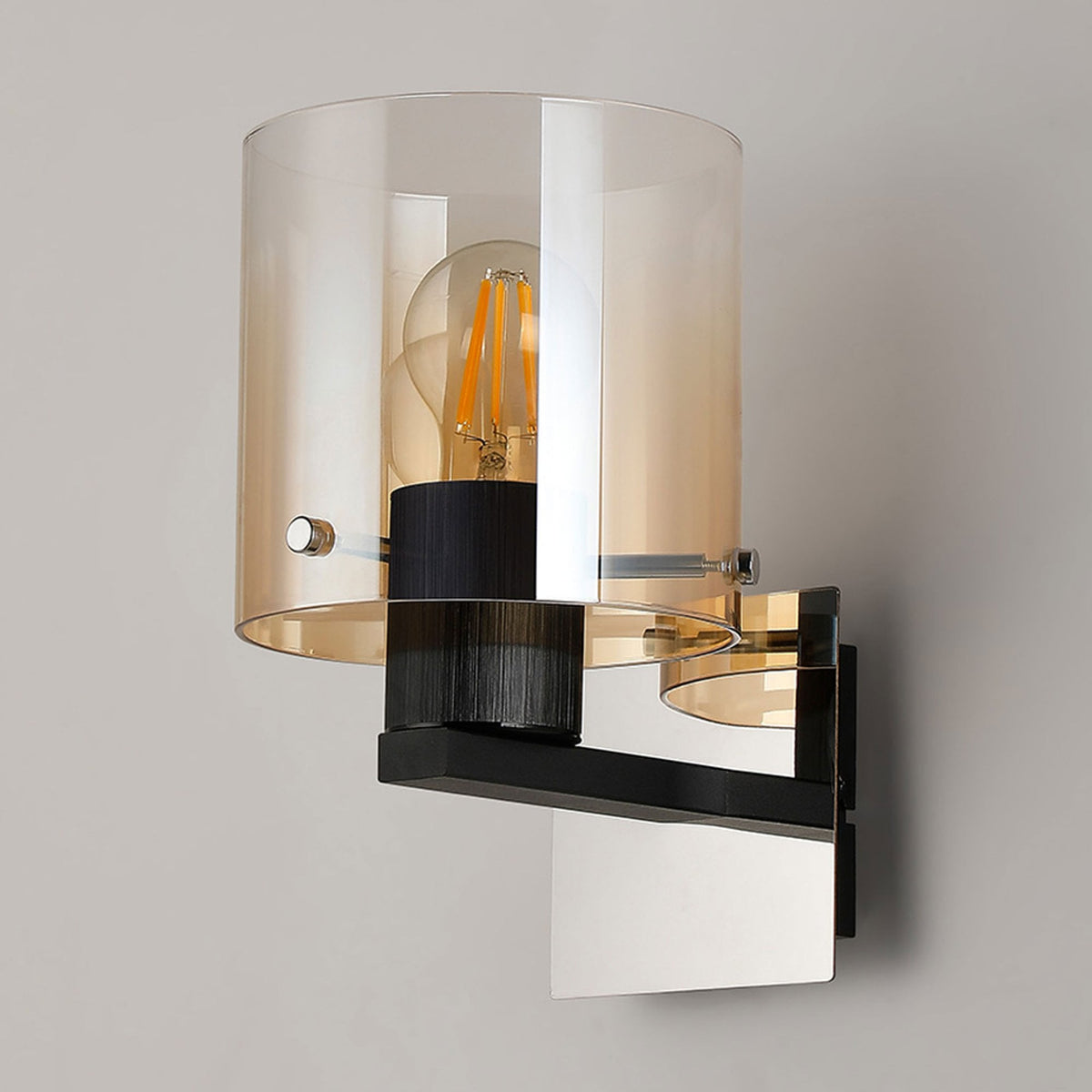 A contemporary wall light with a clear and amber glass shade, black fitting, and illuminated bulb.