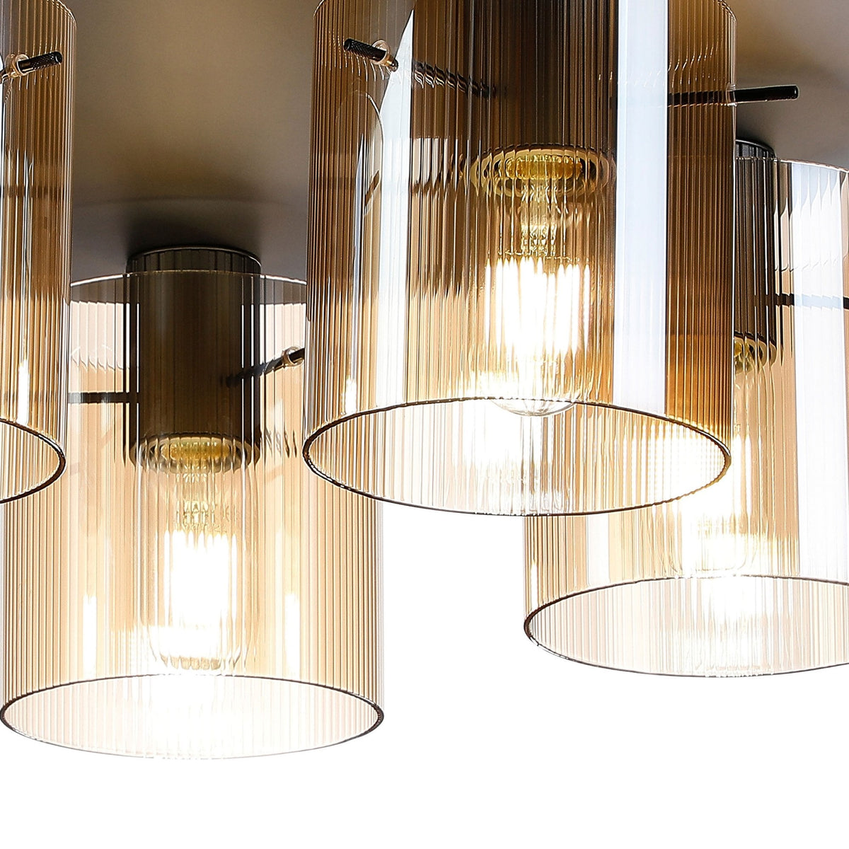 A close-up of a modern five-light ceiling fitting with amber fluted glass shades.