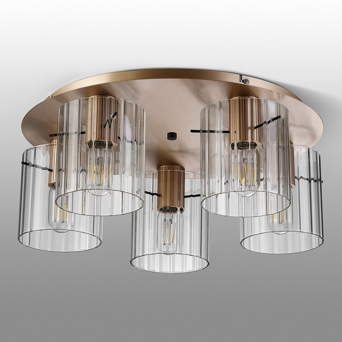 A bright, modern brass ceiling light with five fluted glass shades on a grey background.