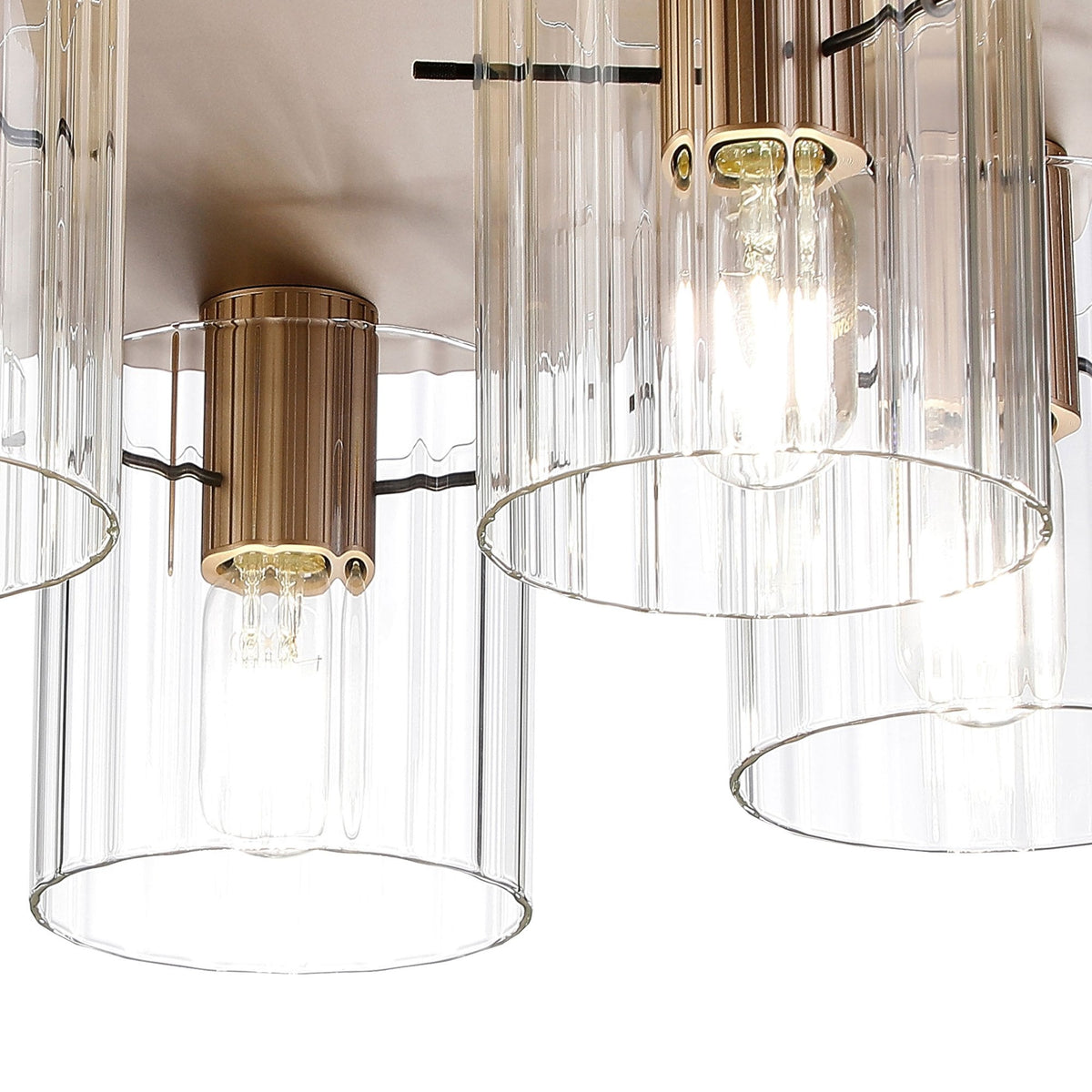 A close-up of a modern brass ceiling light with fluted glass shades.
