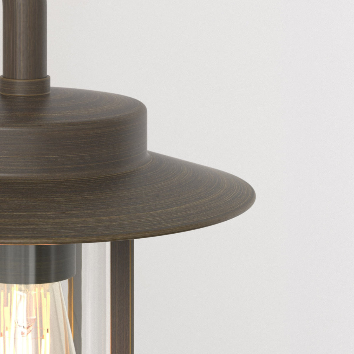 Close-up of a bronze outdoor light fixture with a clear glass shade and exposed filament bulb.