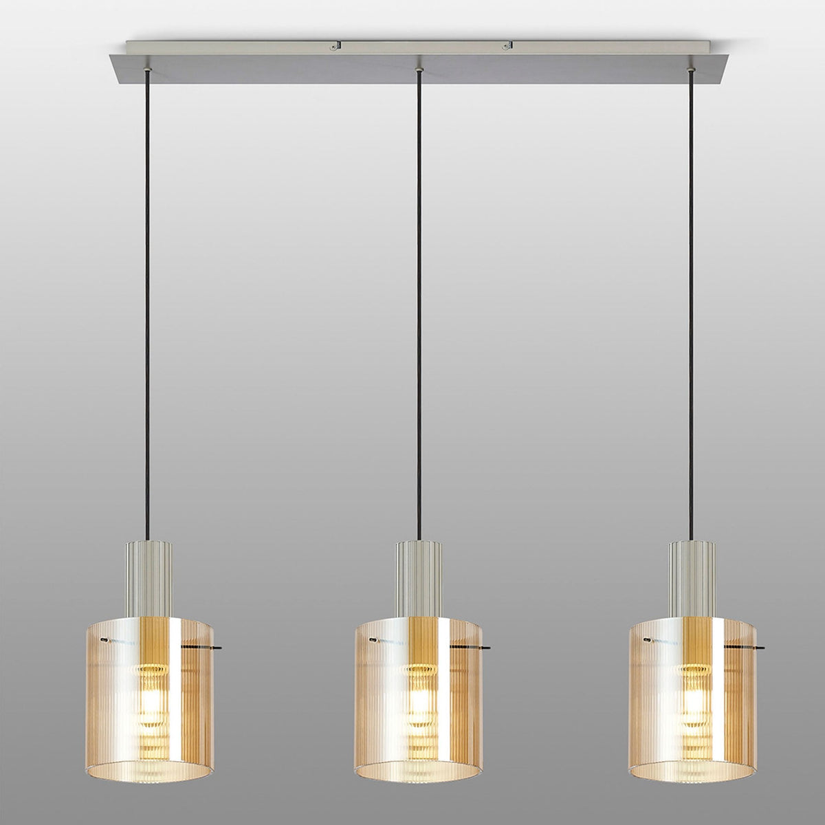 Three cylindrical pendant lights with amber glass shades on a grey background.