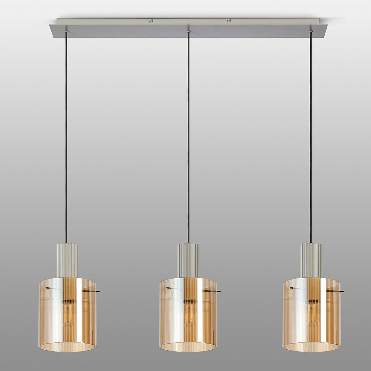 Three cylindrical pendant lights with amber glass shades on a grey background.