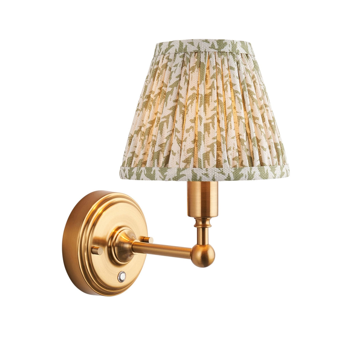 A brass wall sconce with an illuminated pleated green and white botanical print shade.