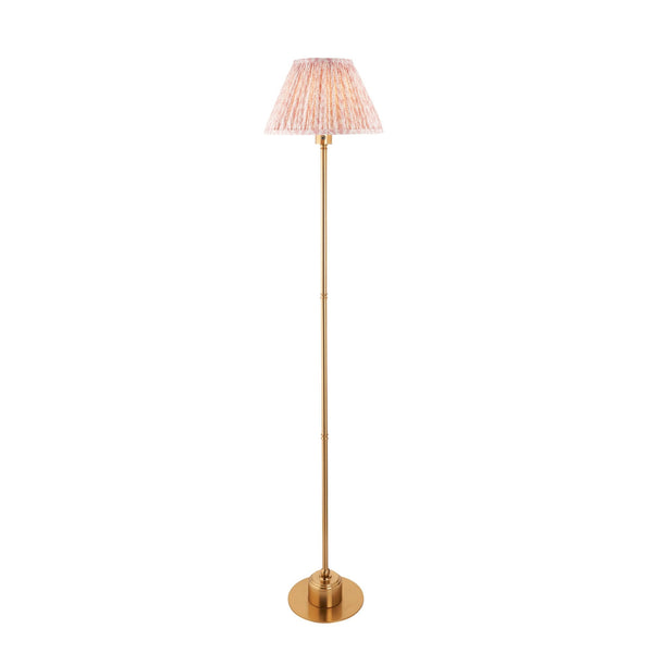 A brass floor lamp with a pleated, patterned lampshade on a white background.