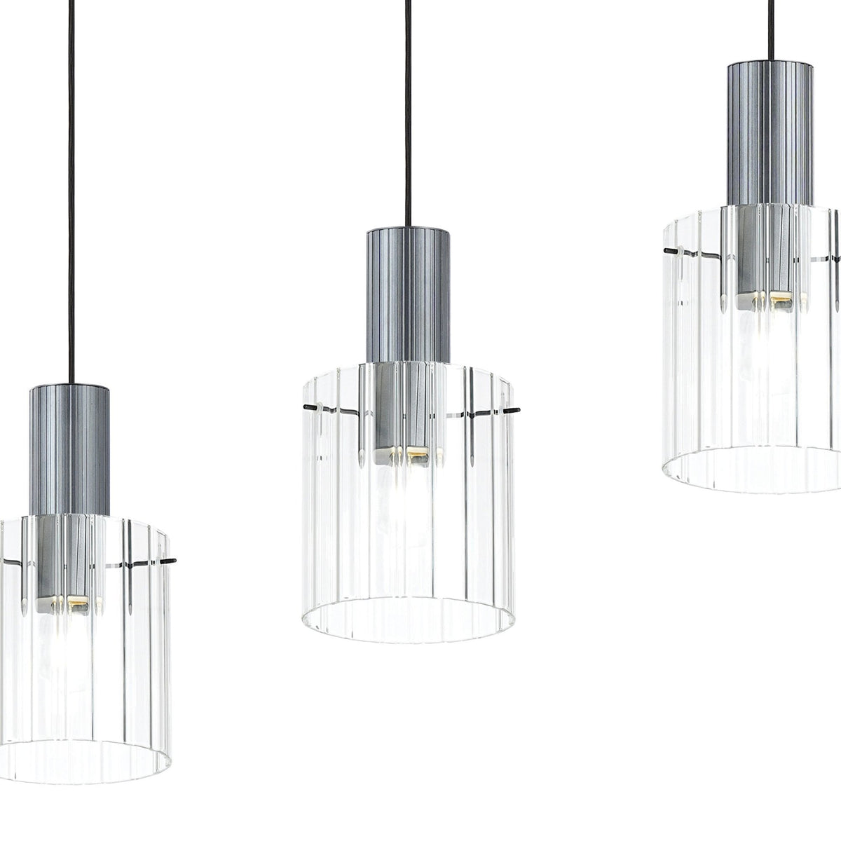 Close-up of three hanging lights with ribbed glass shades on a white background.