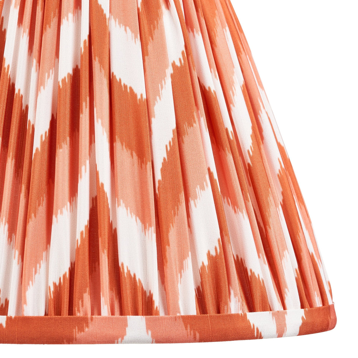 Close-up of a pleated lampshade with an orange and white patterned fabric.